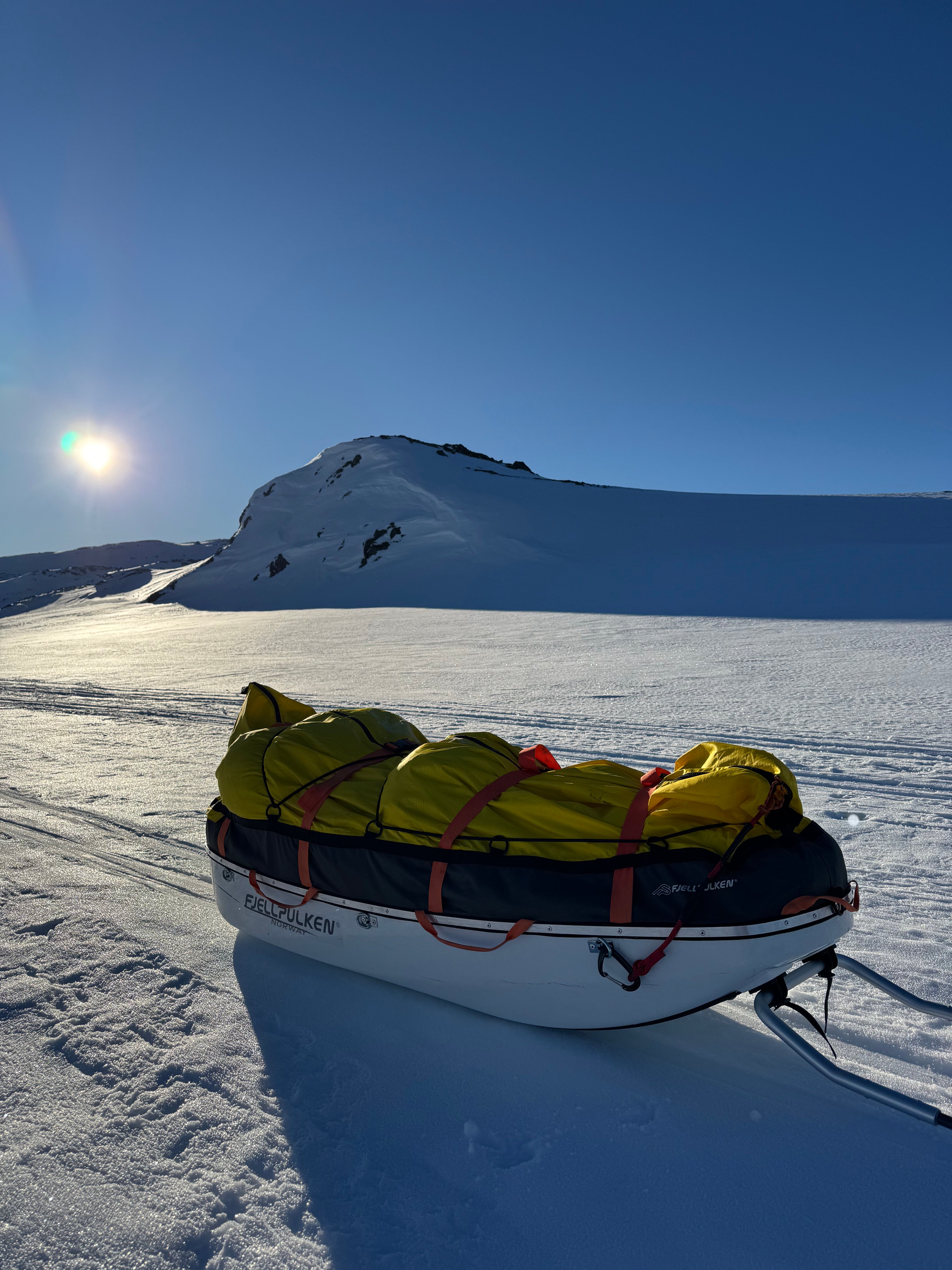 Backpack with yellow sleeping bag on a snowy mountain